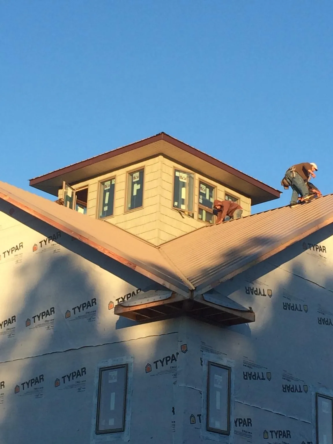 Roofers working around a rooftop cupola on a new metal roof at sunset — Roof Waterproofing in Vienna by Roofing Brothers